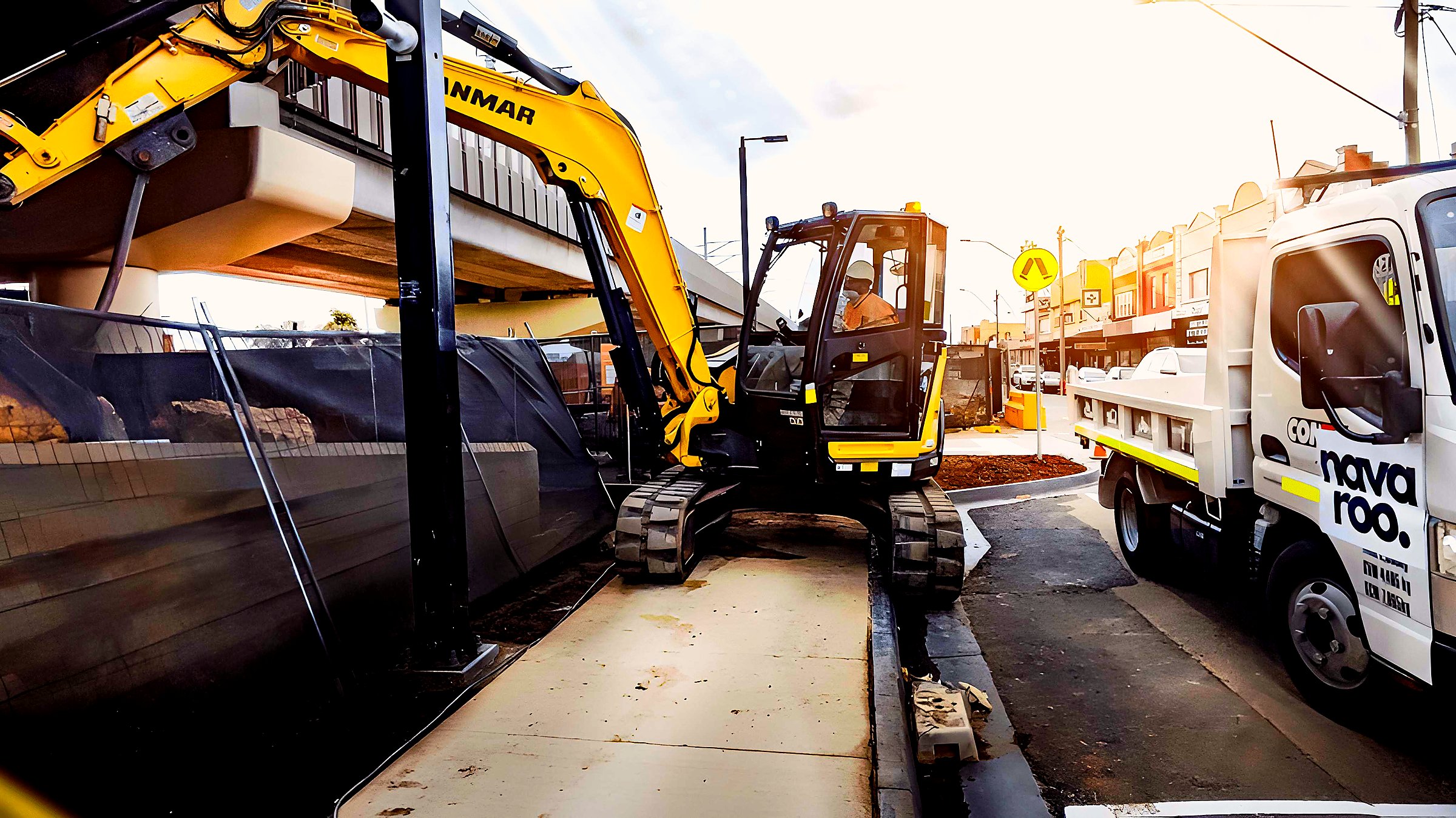 Navaroo excavator and site vehicle working within a constrained external works corridor.