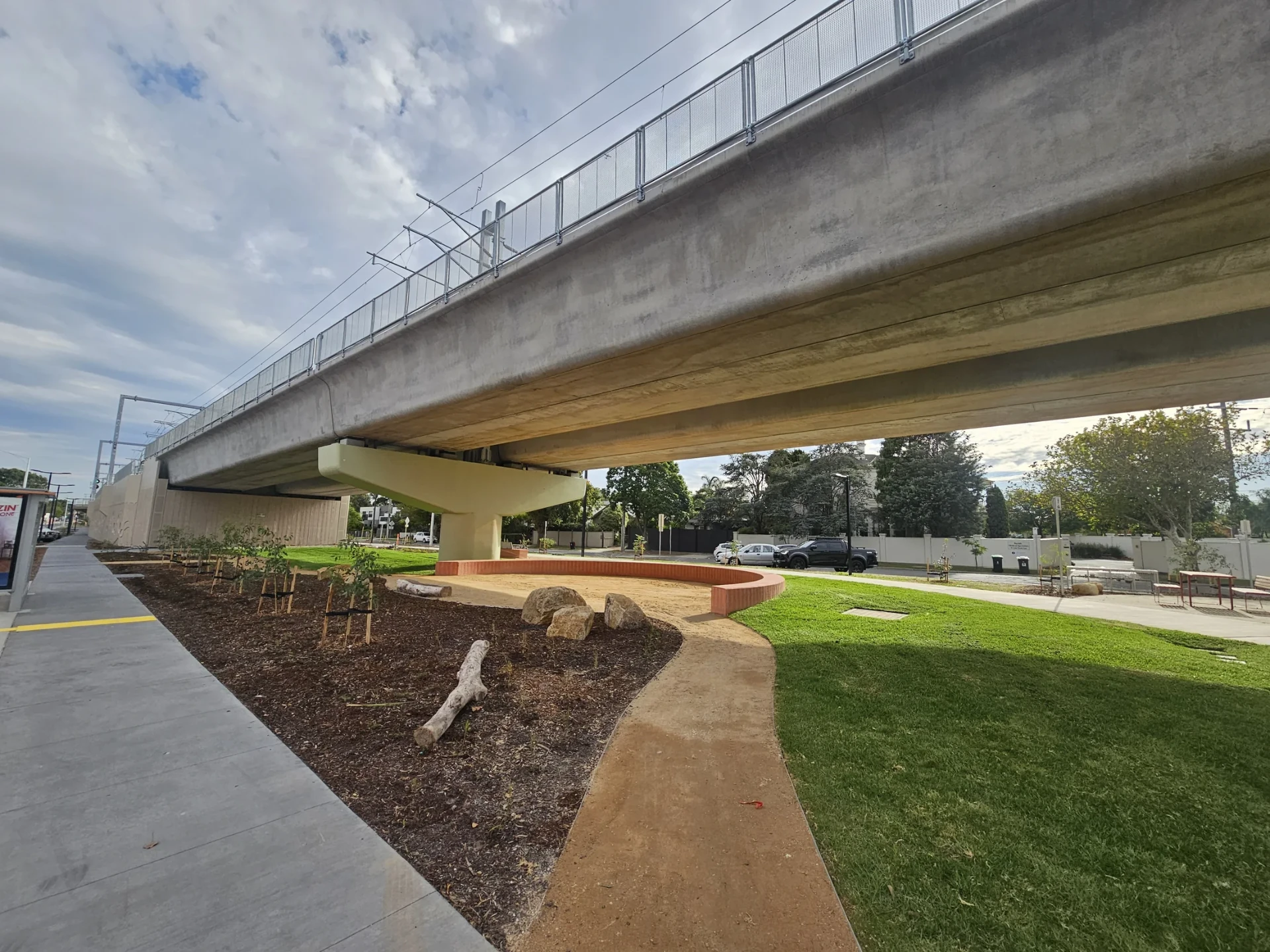 Completed public-realm area with concrete paths, brick edging, boulders and mulched garden beds.